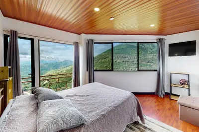 a bedroom with a bed and large windows at El Portal Tarrazu in Santa Cruz
