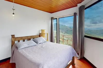 a bedroom with a bed and a large window at El Portal Tarrazu in Santa Cruz