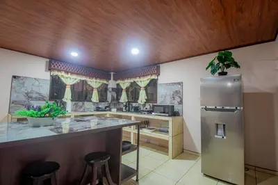 a kitchen with a refrigerator and a counter with stools at Villa Ali Río Cuarto in Río Cuarto