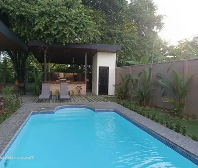 a swimming pool in a yard with a house at Hector House in Uvita