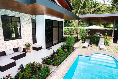 a backyard with a swimming pool and a house at Hector House in Uvita