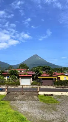a house with a fence and a mountain in the background at Volcano View Apartments in Fortuna