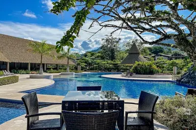 a swimming pool with a table and chairs next to it at Villa Paraiso do Mar in Jacó