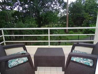 a patio with two chairs and a table on a porch at Paradise Jaco Beach Apartment in Jacó