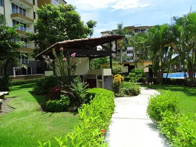 a garden with a walkway in front of a building at Paradise Jaco Beach Apartment in Jacó