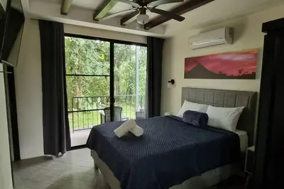 a bedroom with a bed and a large window at Villas Töcu - Casa Colibrí in Fortuna