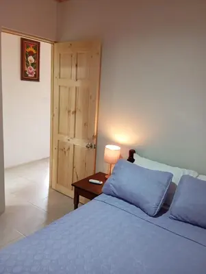 a bedroom with a blue bed and a table with a lamp at Apartamentos La Paz in Liberia