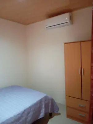 a bedroom with a bed and a wooden cabinet at Apartamentos La Paz in Liberia