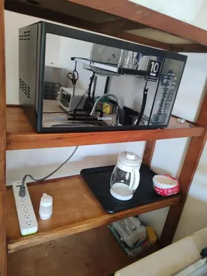 a microwave on a wooden shelf with a remote control at Apartamentos La Paz in Liberia