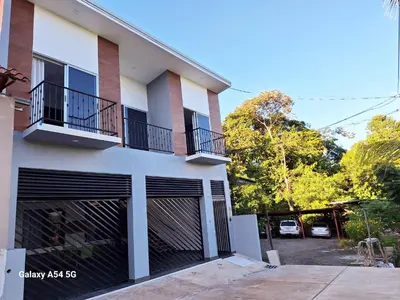 a white building with black garage doors and a parking lot at Casa Victoria CR in San Isidro