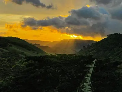 a sun setting over a mountain with a train track at Casa Curré Monteverde in Monteverde Costa Rica