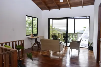 a living room with a table and chairs and windows at Casa Curré Monteverde in Monteverde Costa Rica