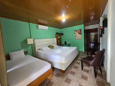 a bedroom with two beds and a chair in it at Tortuguero Hill Rooms in Tortuguero