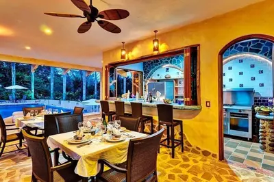 a dining room with tables and chairs and a kitchen at Stunning House! Villa Kalapiti - Blue Zone Costa Rica in Delicias