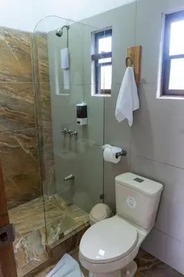 a bathroom with a toilet and a glass shower at Hotel Pura Natura Riverside Tortuguero in Tortuguero