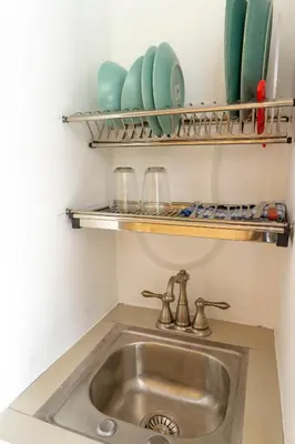 a sink in a kitchen with shelves above it at Hotel Pura Natura Riverside Tortuguero in Tortuguero