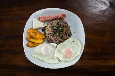 a plate of food with eggs and meat and bread at Hotel Pura Natura Riverside Tortuguero in Tortuguero