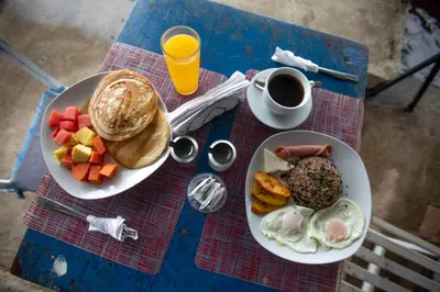 a table with two plates of breakfast food and a cup of coffee at Hotel Pura Natura Riverside Tortuguero in Tortuguero