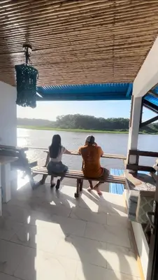 two people sitting on a bench on a boat at Hotel Pura Natura Riverside Tortuguero in Tortuguero