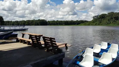 a dock with chairs and a boat on a lake at Hotel Pura Natura Riverside Tortuguero in Tortuguero