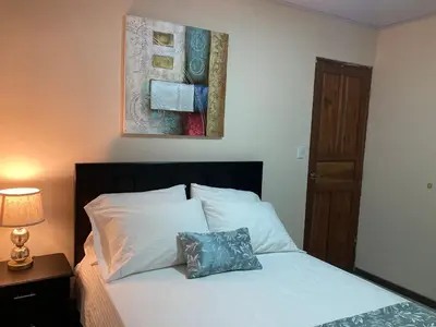 a bedroom with a white bed with a pillow on it at Hospedaje Ana Lu 1 Only 10 minutes from airport in Alajuela City