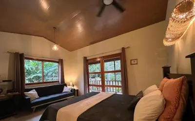 a bedroom with a bed and a couch and windows at Siquirres Mountain Lodge in Siquirres