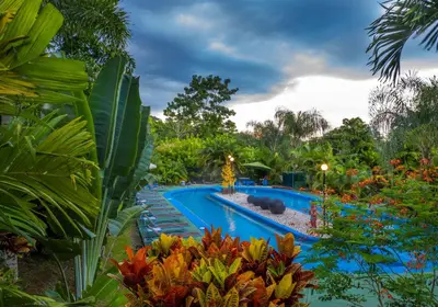 a swimming pool in a garden with plants at Hotel Heliconias Nature Inn & Hot Springs in Fortuna