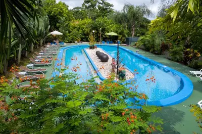 a swimming pool with lounge chairs and a resort at Hotel Heliconias Nature Inn & Hot Springs in Fortuna