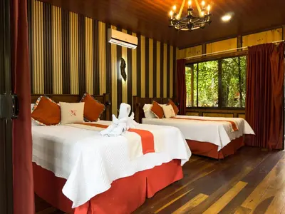 a bedroom with two beds and a chandelier at Hotel Heliconias Nature Inn & Hot Springs in Fortuna