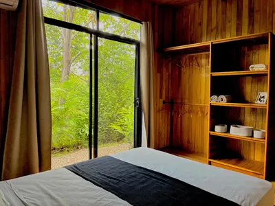a bedroom with a bed and a large window at Cabaña Grande océan and jungle Infinity swim pool in Santa Teresa Beach