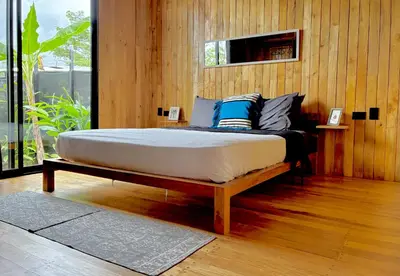 a bed in a room with a wooden wall at Cabaña Grande océan and jungle Infinity swim pool in Santa Teresa Beach
