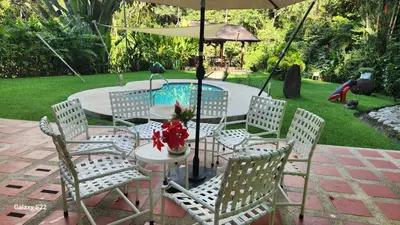 a table and chairs with an umbrella next to a pool at Yethan house in Uvita