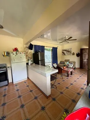 a kitchen and living room with a refrigerator and a table at Yethan house in Uvita