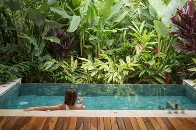 a woman sitting in a swimming pool in a garden at Nayara Springs - Adults Only in Fortuna