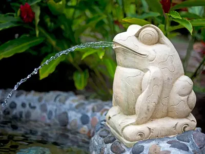 a statue of a frog sitting on top of a fountain at Nayara Springs - Adults Only in Fortuna