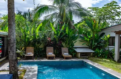 a pool in front of a house with two chairs and a table at Maoritsio Garden Studios in Santa Teresa Beach