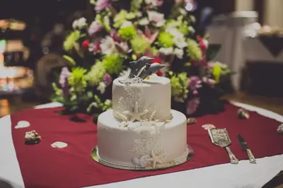 a white wedding cake on a table with flowers at Guacamaya Lodge in Paraíso