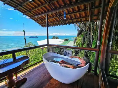 a woman in a bath tub on a balcony with the ocean at Hotel Costa Verde in Manuel Antonio