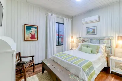 a white bedroom with a bed and a window at Hotel Punta Descartes in La Cruz