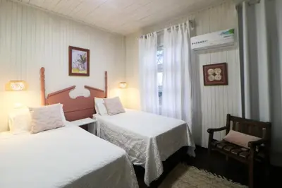 a bedroom with two beds and a chair and a window at Hotel Punta Descartes in La Cruz