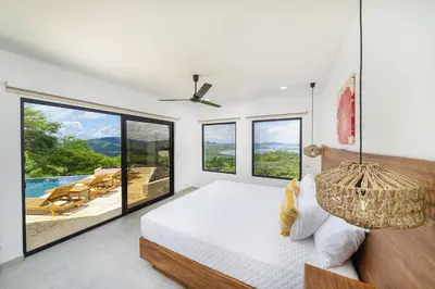 a bedroom with a bed and large windows at Villa Vista Pacifico - Serene Villa, Ocean View Pool, Rooftop Deck, 5 BR in Potrero