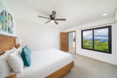a bedroom with a bed with a ceiling fan and a window at Villa Vista Pacifico - Serene Villa, Ocean View Pool, Rooftop Deck, 5 BR in Potrero