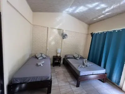 two beds in a room with blue curtains at The Secret Eco Lodge in Tortuguero