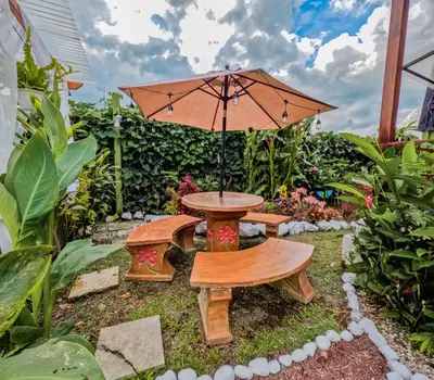 a table and bench with an umbrella in a garden at Arenal Tiny Houses - STAR in Fortuna