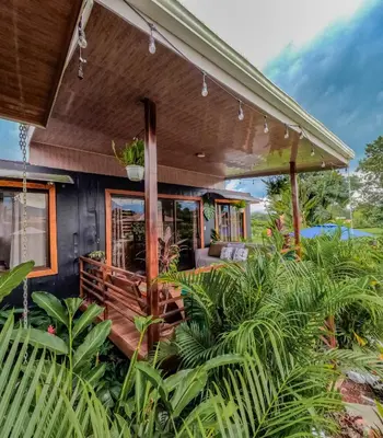 a house with a wrap around porch with plants at Arenal Tiny Houses - STAR in Fortuna