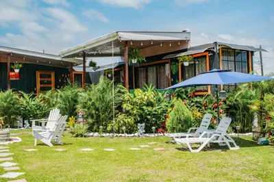 a group of chairs and an umbrella in front of a house at Arenal Tiny Houses - STAR in Fortuna