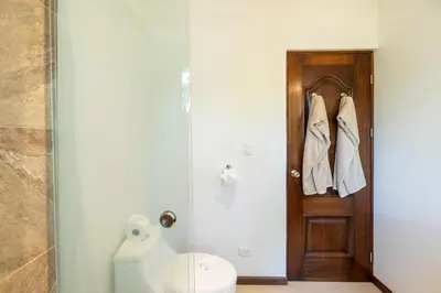 a bathroom with a toilet and a wooden door at Casa Callie- 3 Bedroom House With Pool in Tamarindo