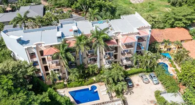 an aerial view of a resort with a pool and palm trees at Tamarindo Gem: 1BR Apt in Heart! in Tamarindo