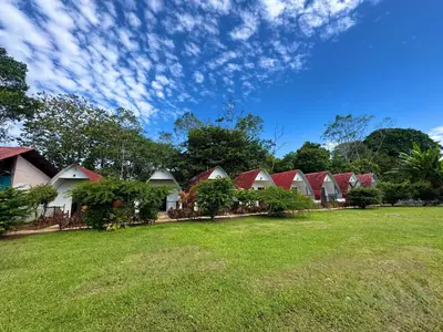 a row of houses with red roofs on a grass field at Eco Hotel Villas del Tortuguero in Cariari