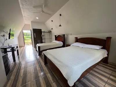 a bedroom with two beds and a desk in it at Eco Hotel Villas del Tortuguero in Cariari
